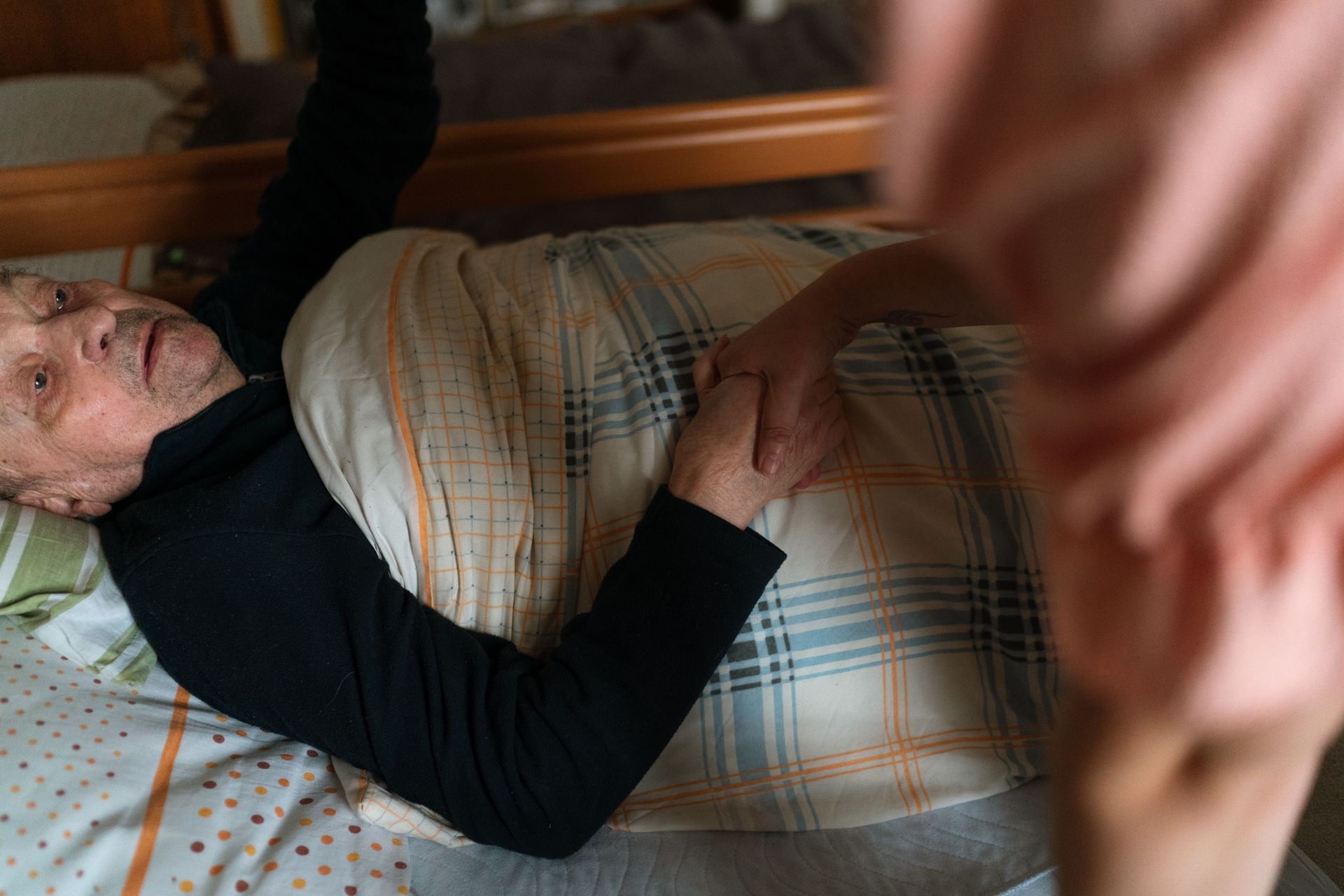 A caregiver holding hands with a senior adult, providing support and reassurance at home.